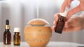 Modern aroma oil diffuser on the white table. Spa concept for body and health care. female is adding essential oil to an Royalty Free Stock Photo