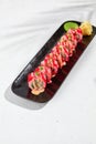 Modern asian food - maki with tobiko on black plate on white concrete background. Sushi roll with  tobiko caviar and spicy sauce Royalty Free Stock Photo