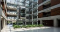 Modern atrium interior with a central glass elevator shaft surrounded by lush green Royalty Free Stock Photo