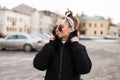 Modern attractive young hipster woman in winter stylish clothes with a hairdress with a bandana in sunglasses in the city Royalty Free Stock Photo