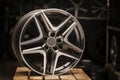 Modern automotive alloy wheel made of aluminum on a black background, industry. on a textured wooden table. Designer Royalty Free Stock Photo