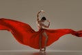 Modern ballet. Handsome young male ballet dancer performing with red silk fabric against grey studio background Royalty Free Stock Photo