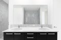 A bathroom with a black cabinet, marble countertop, and subway tile showers.