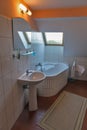 Modern bathroom with corner bath, washbasin and window.