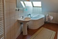 Modern bathroom with corner bath, washbasin and window. Royalty Free Stock Photo