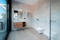 Modern bathroom with a glass bathtub and luxury washbasin. The walls and floor are covered with modern tiles