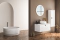 Modern bathroom interior with beige walls, white basin with oval mirror, bathtub and parquet floor. Royalty Free Stock Photo