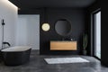 Modern bathroom interior with concrete floor, black bathtub, and oval mirror, marble basin, Royalty Free Stock Photo