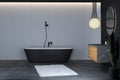 Modern bathroom interior with concrete floor, black bathtub, and oval mirror, marble basin, pendant light, Royalty Free Stock Photo