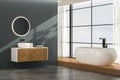 Modern bathroom interior with concrete flooring, white bathtub and white oval sink, front view.