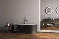 Modern bathroom interior with dark brown parquet floor, white and black bathtub and marble wash basin Royalty Free Stock Photo