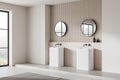 Modern bathroom interior with dual sinks, round mirrors, and a view through the window, on a light background, concept of a Royalty Free Stock Photo