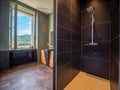 Modern bathroom interior with a large window and a walk-in black tiled shower