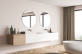 Modern bathroom vanity with two round mirrors on beige wall. Corner view