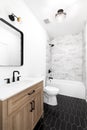 A modern bathroom with a wood cabinet and black tile floor. Royalty Free Stock Photo