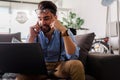 Young businessman working on laptop computer while sitting on sofa at home Royalty Free Stock Photo