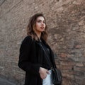 Modern beautiful young woman in an elegant coat in a fashionable t-shirt in white jeans with a leather bag posing Royalty Free Stock Photo