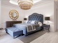 Modern bed in classic blue style with bedside table and lamp. Large glass chandelier over. A dresser with a decor and a golden Royalty Free Stock Photo