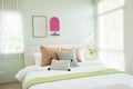 Modern bedroom with green and pink pillows on bed. Royalty Free Stock Photo