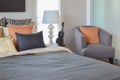 Modern bedroom interior with orange pillow on grey chair and bedside table lamp Royalty Free Stock Photo