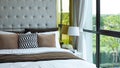 Modern bedroom beside window in the morning, pillows and cushions in white, beige and brown color tone on bed in luxury bedroom Royalty Free Stock Photo