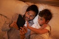 Modern bedtime story. A father reading a bedtime story to his son from an e-reader. Royalty Free Stock Photo