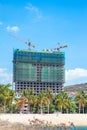 Modern big residential or office high rise building under construction against blue sky with tower crane near sea beach Royalty Free Stock Photo