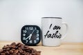 Modern black alarm clock next to coffee mug Royalty Free Stock Photo