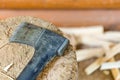 Modern black axe in the log and wooden chips after cutting firewood for winter near pile wooden house