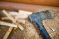 Modern black axe in the log and wooden chips after cutting firewood for winter near pile wooden house