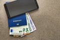 Modern black cellphone, Euro money banknotes bills and travel passport on copy space background. Travelling light, comfortable