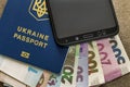 Modern black cellphone, money hryvnia banknotes bills and ukrainian travel passport on copy space background. Travelling light,