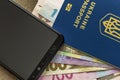 Modern black cellphone, money hryvnia banknotes bills and ukrainian travel passport on copy space background. Travelling light,