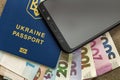 Modern black cellphone, money hryvnia banknotes bills and ukrainian travel passport on copy space background. Travelling light,