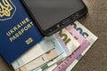 Modern black cellphone, money hryvnia banknotes bills and ukrainian travel passport on copy space background. Travelling light,