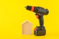Modern black cordless screwdriver with rechargeable battery and wooden house