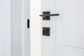 Modern black door handle on white wooden door in interior. Knob close-up elements. Door handle, fittings for interior design Royalty Free Stock Photo