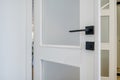 Modern black door handle on white wooden door in interior. Knob close-up elements. Door handle, fittings for interior design Royalty Free Stock Photo