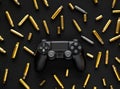 Modern black gamepad on a black background among the spent cartridges. Game concept. Shooter game