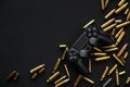 Modern black gamepad on a black background among the spent cartridges. Game concept. Shooter game