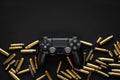 Modern black gamepad on a black background among the spent cartridges. Game concept. Shooter game