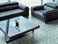 Modern black leather sofa and black glass table on tile flooring in living room Royalty Free Stock Photo