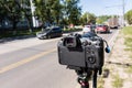 Modern black professional mirrorless camera on tripod or monopod shooting city car traffic at summer day