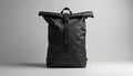 Modern black rolltop backpack made of durable nylon fabric. Features secure buckle closure, adjustable straps for comfort. Royalty Free Stock Photo