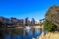 A modern black, white and gray apartment building with a lake with a water fountain in front surrounded by bare winter trees Royalty Free Stock Photo