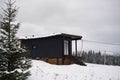 Modern Black wooden tiny cabin in snowy pine forest Royalty Free Stock Photo