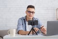 Modern blogger, teacher or tutor and technology for working at home with students. Young man with glasses chatting