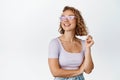 Modern blond girl in sunglasses, smiling and looking aside, wearing summer outfit, standing happy against white