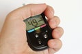 Modern blood glucose meter held in left hand with healthy person preprandial glucose value
