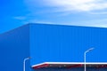 Modern blue aluminum industrial factory building with awning and 2 solar power street light posts against blue sky Royalty Free Stock Photo